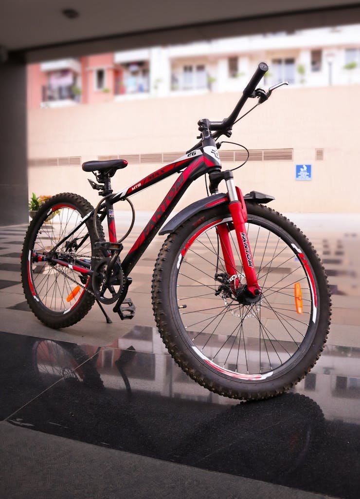 Photo by Tony Sebastian A modern red and black mountain bike parked indoors showcasing its sturdy frame and design.