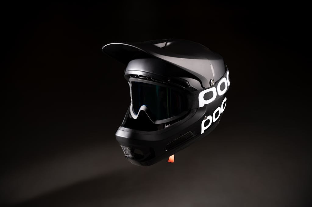 Photo by Jan Kopřiva A sleek black bicycle helmet with goggles isolated against a dark backdrop.