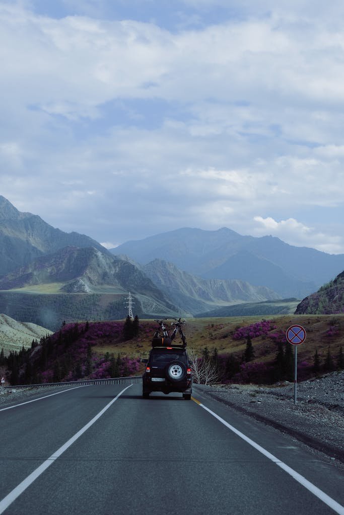 Photo by Yulia Pribytkova Car with Bicycles on Roof Rack Heading Towards Mountains