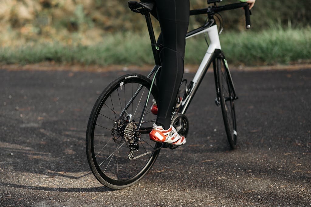 Photo by Pavel Danilyuk Cyclist with red cleats riding a road bike on an outdoor path.