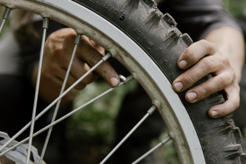Mechanic using hands to repair a bicycle tire in an outdoor setting.