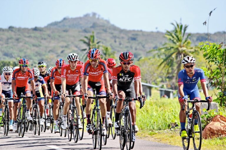 A group of competitive cyclists racing outdoors on a sunny day in the countryside.