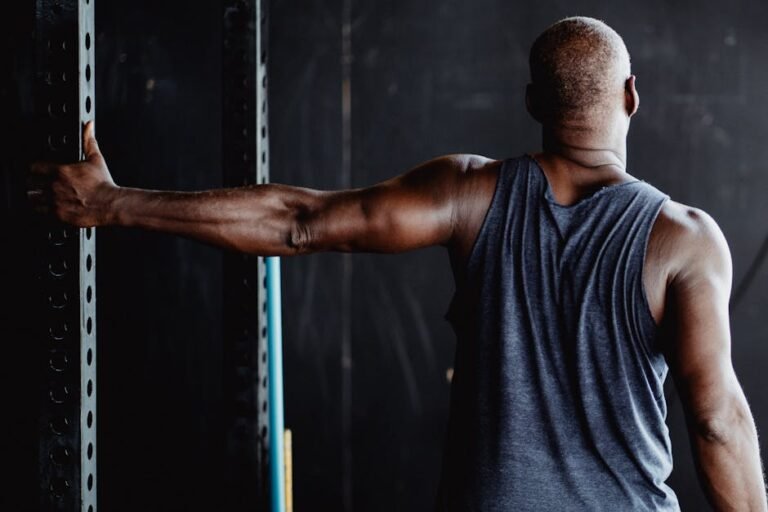 An athletic man stretching his arm in a gym, showcasing strength and flexibility.