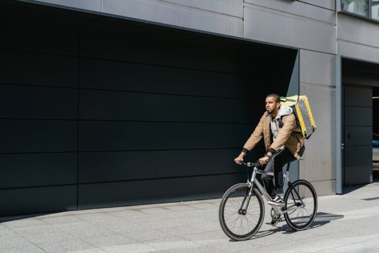 Delivery cyclist with backpack rides through city street, showcasing modern urban logistics.