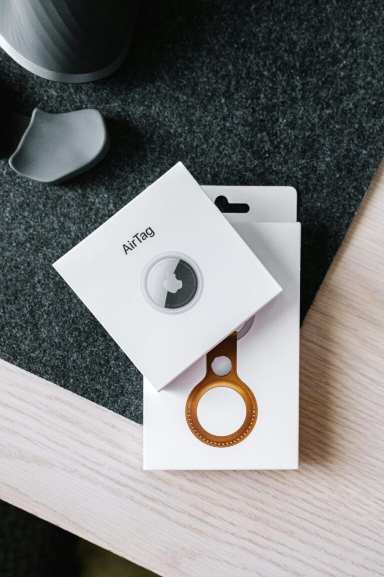 Overhead shot of AirTag and leather key ring packaging on wooden surface.