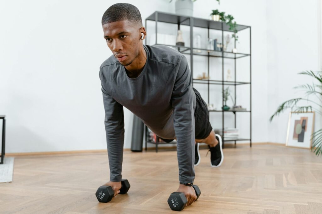 pexels-photo-8033047-8033047 Man performing push-up exercises with dumbbells indoors. Fitness and healthy lifestyle concept.